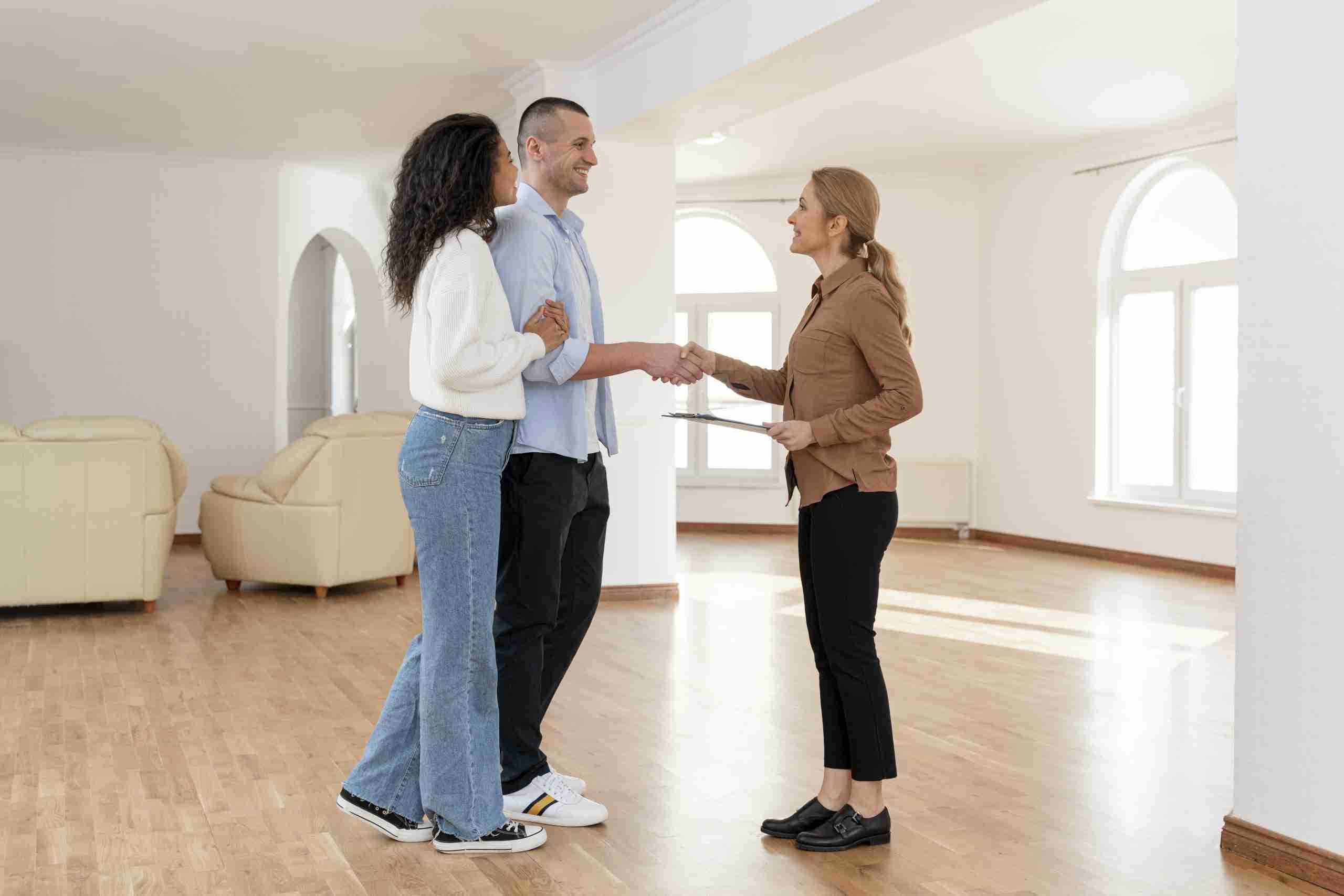 Hombre y mujer llegan a un acuerdo con una agente inmobiliaria durante la visita de una nueva casa