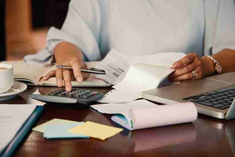 Manos de mujer calculan impuestos sobre vivienda heredada en portátil.