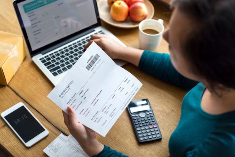 Mujer preocupada con el recibo de la hipoteca, el portátil, el móvil y la calculadora.