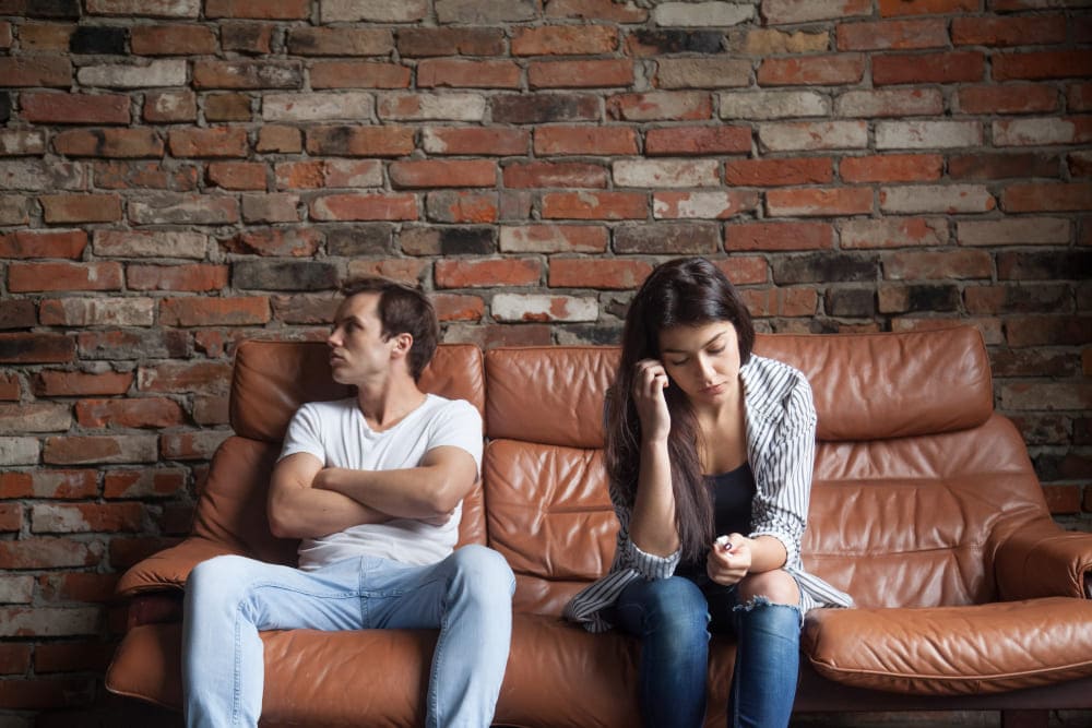 Un matrimonio sobre un sofá divorciados, peleándose por quien se queda con la casa