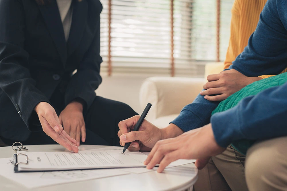 Asesor hipotecario muestra contrato puente a pareja firmando con bolígrafo