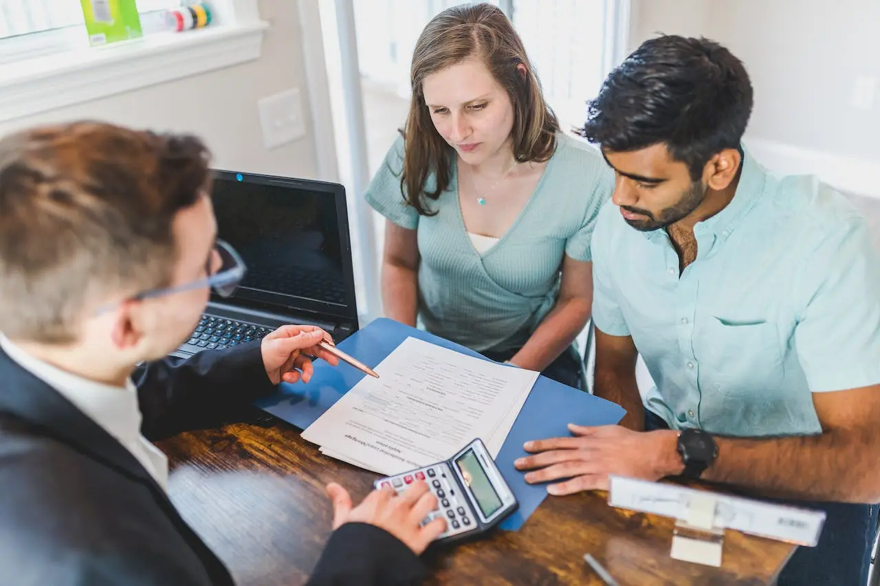 Asesor hipotecario muestra requisitos de ayudas hipotecarias a pareja.