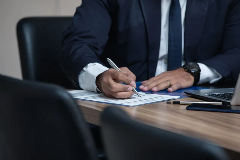 Un hombre en traje firma un documento notarial en su oficina