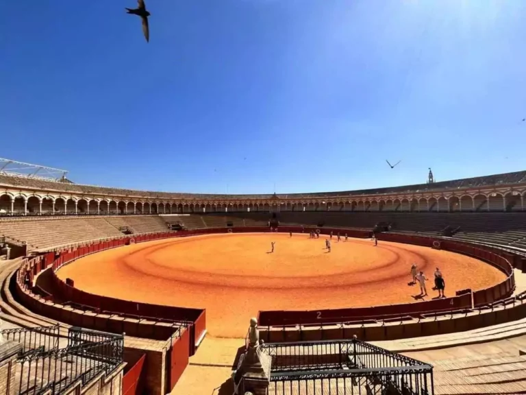 Plaza de Toros de la Maestranza en el Arenal en Sevilla, cielo despejado, personas en el ruedo.