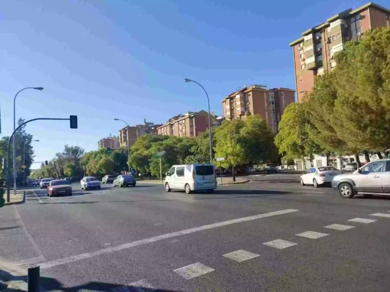 Cruce de calles en la Avenida de la Paz en Sevilla, con coches y edificios residenciales al fondo