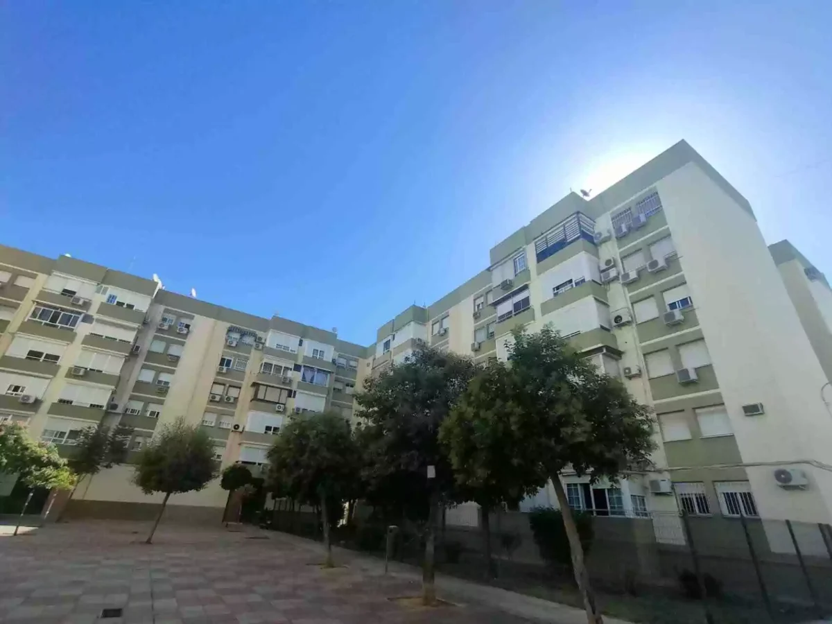 Edificios residenciales en el barrio de Los Príncipes Sevilla, con árboles y cielo despejado.