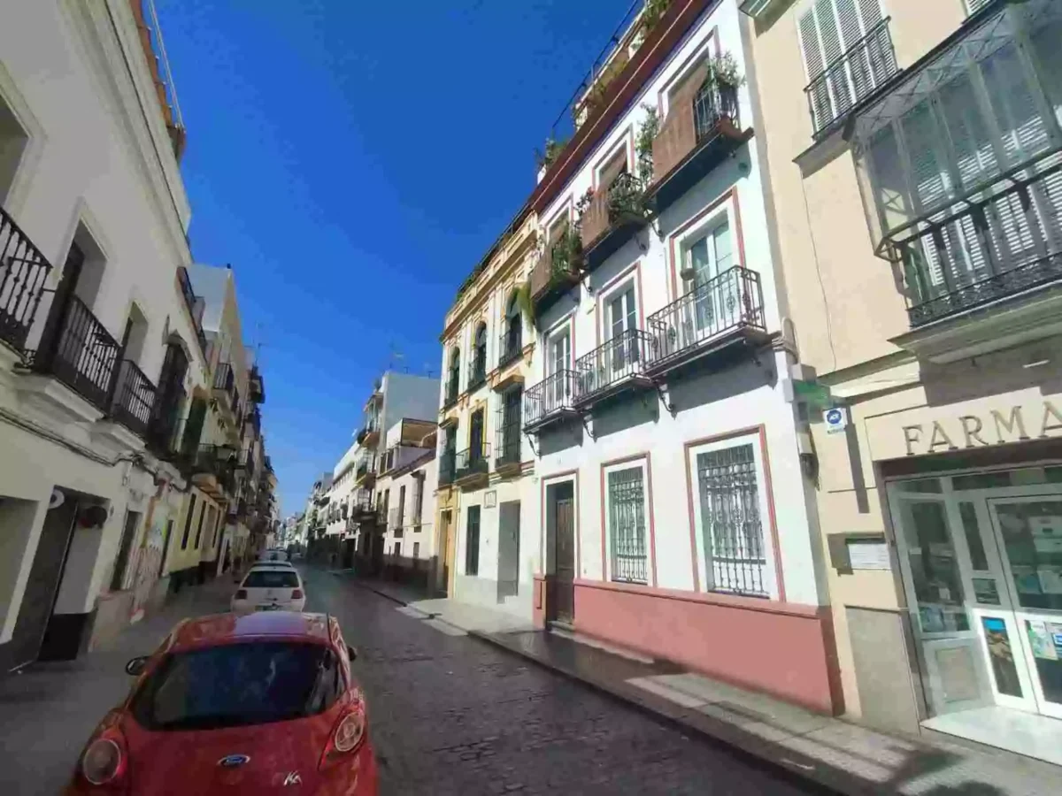 Calle con edificios residenciales en el barrio de San Lorenzo en Sevilla, bajo un cielo despejado.