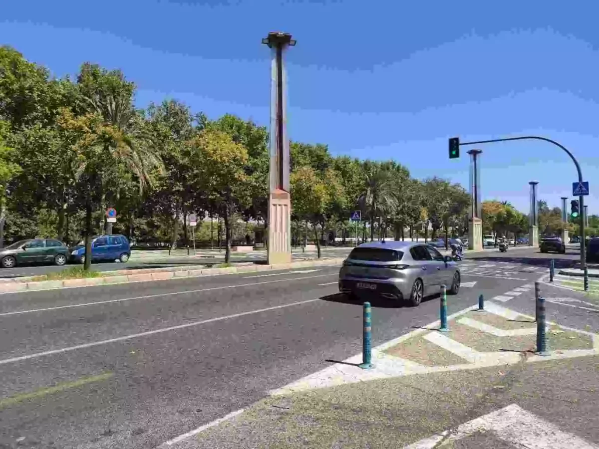 Avenida del barrio de San Lorenzo en Sevilla, con coches, palmeras y cielo despejado.