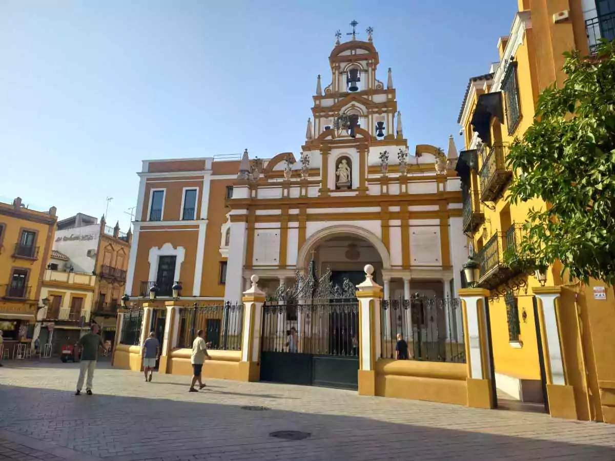 Edificio católico blanco y rosado con gente entrando y saliendo