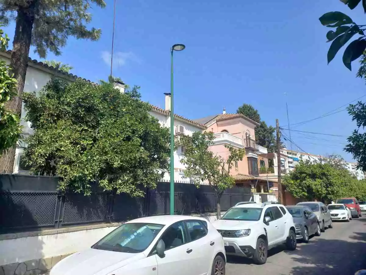 Casas de dos plantas valladas y con coches aparcados en la calle