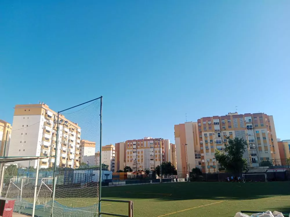 Campo de fútbol de césped artificial del polideportivo Las Almenas. Cerca hay edificios del barrio.