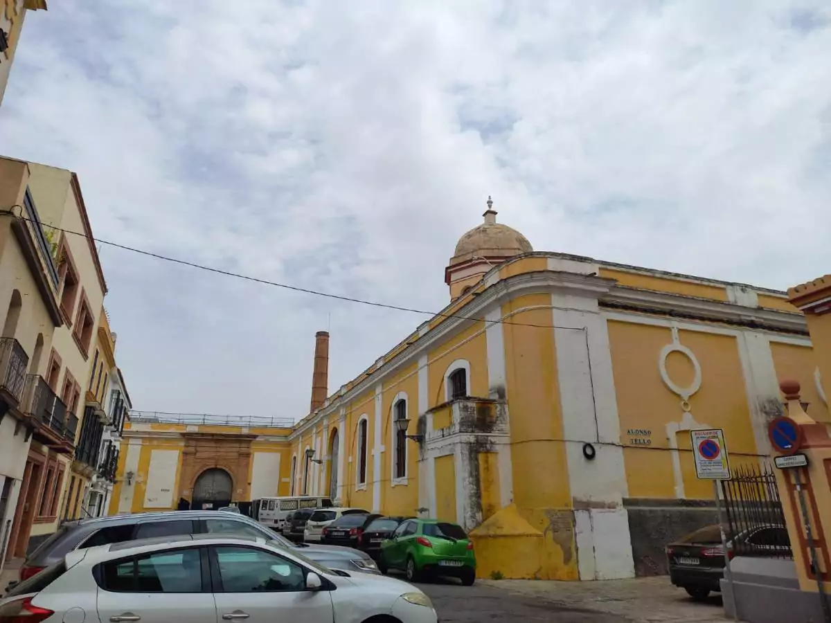 Edificio amarillo y blanco de una planta y coches aparcados en la acera