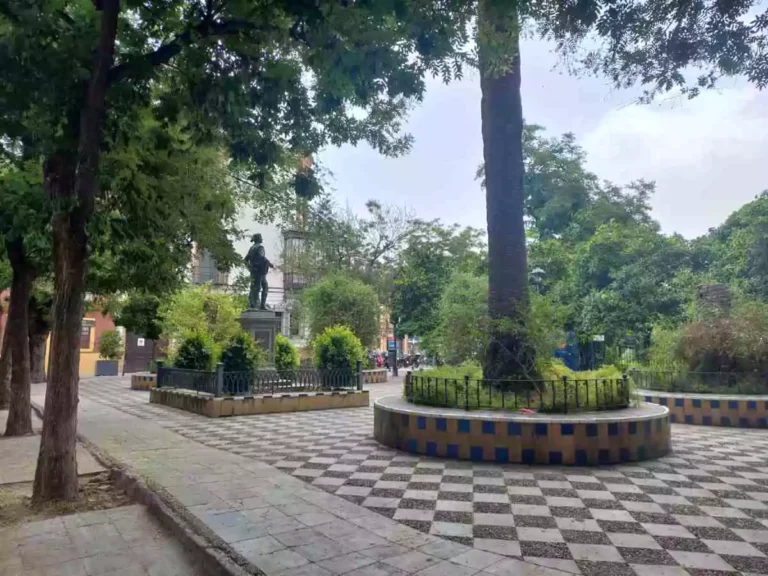 Plaza en Santa Cruz con vegetación y una estatua de un hombre en el centro.