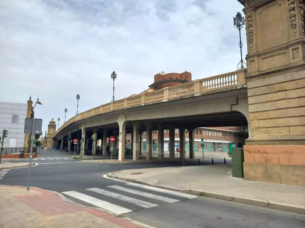 Puente de piedra con adornos, con una carretera debajo y farolas en lo alto del puente.