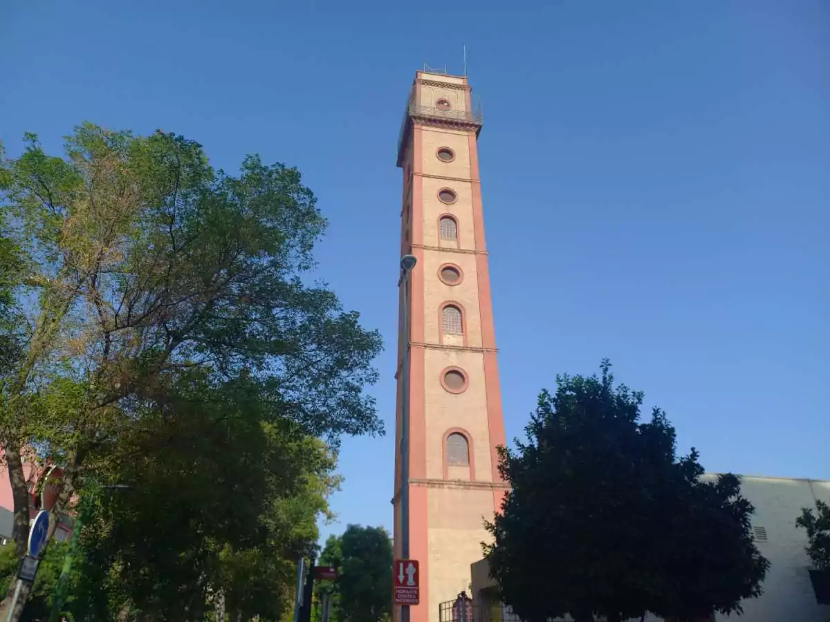 Torre alta de colores rosados con un jardín que la rodea