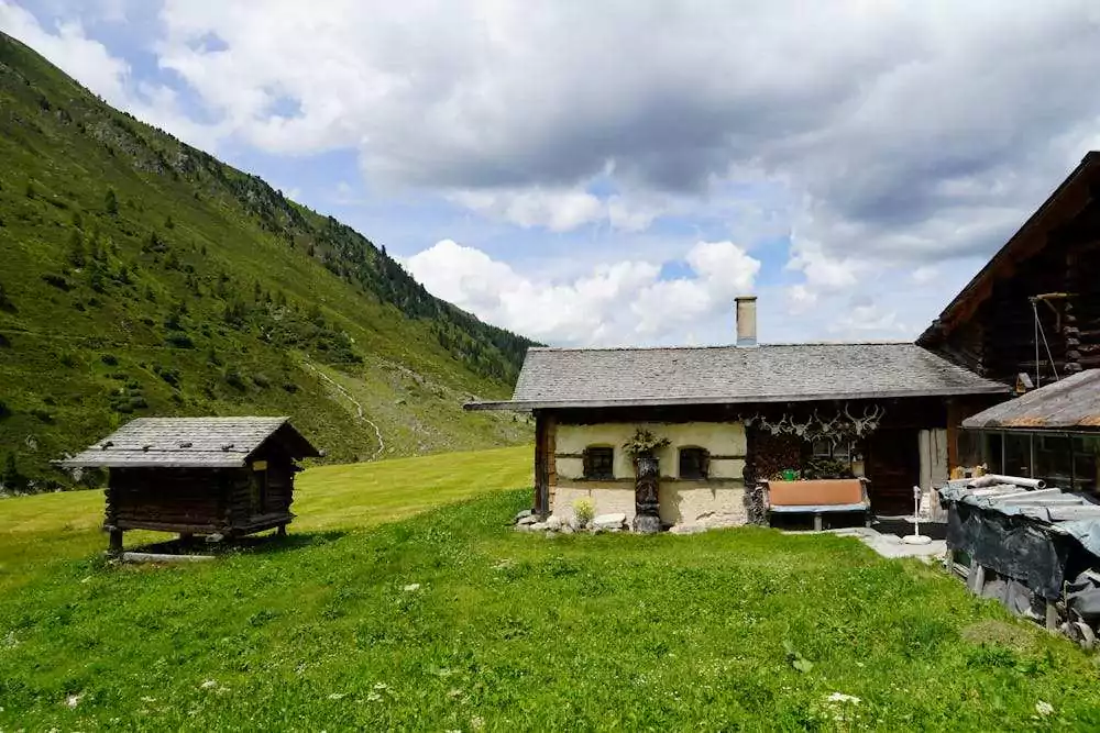 Casa rural en prado verde con montaña, destacando la diferencia entre chalet adosado y pareado.